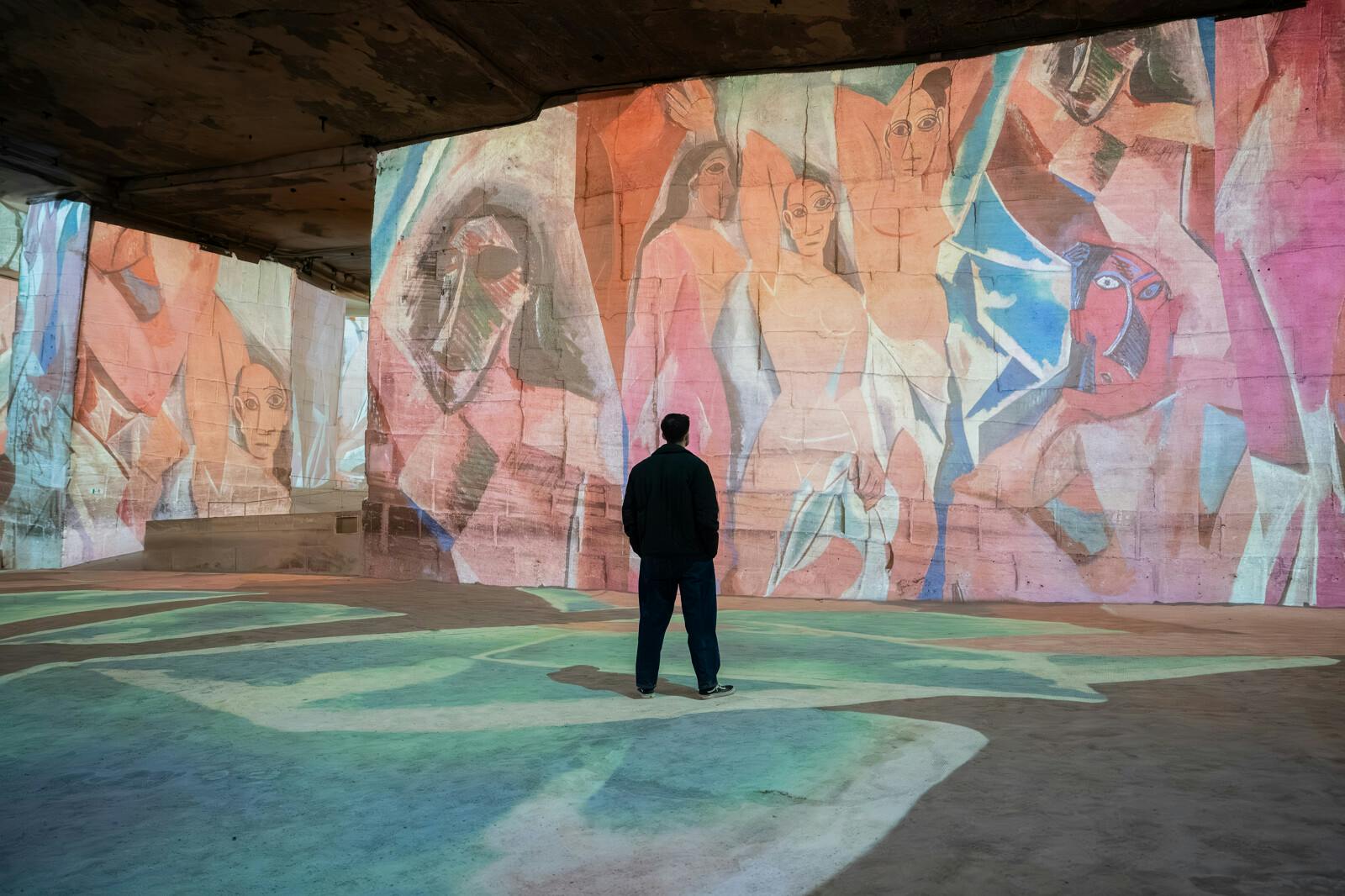 Un vizitor contemplând proiecțiile monumentale de la Carrières des Lumières