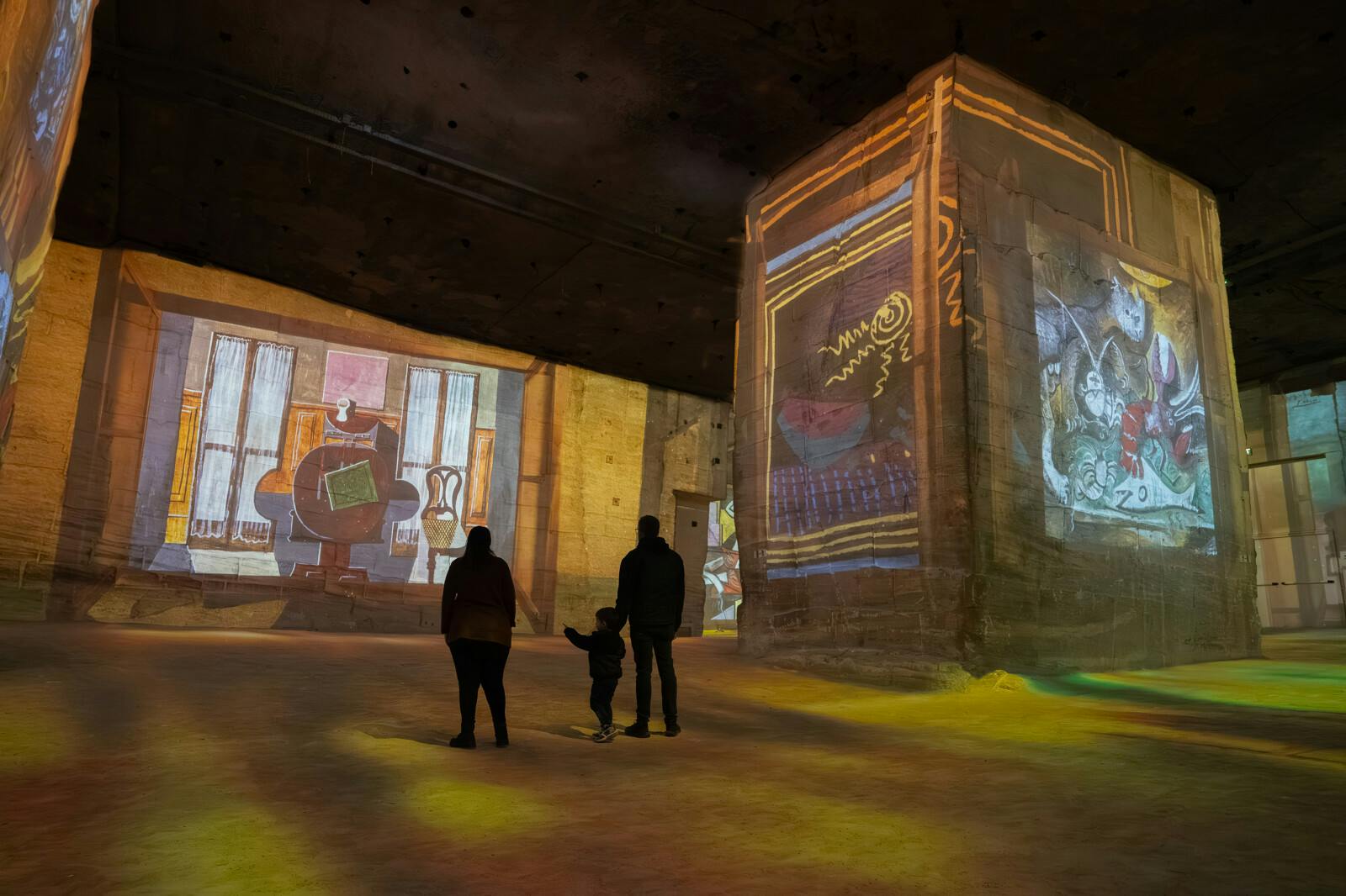 Vizitatori contemplând proiecțiile artistice la Carrières des Lumières